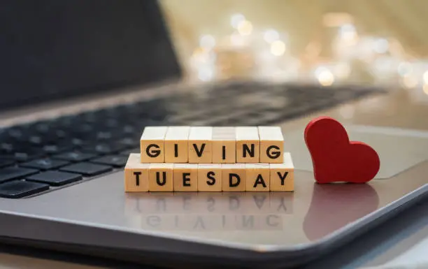 Photo of GIVING TUESDAY letter blocks concept on laptop keyboard
