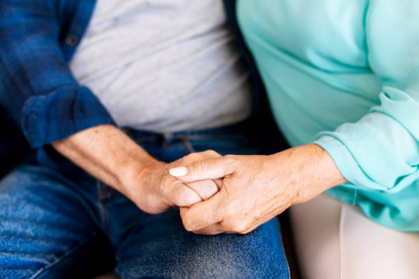istock Senior couple holding hands sitting at home 1273898959