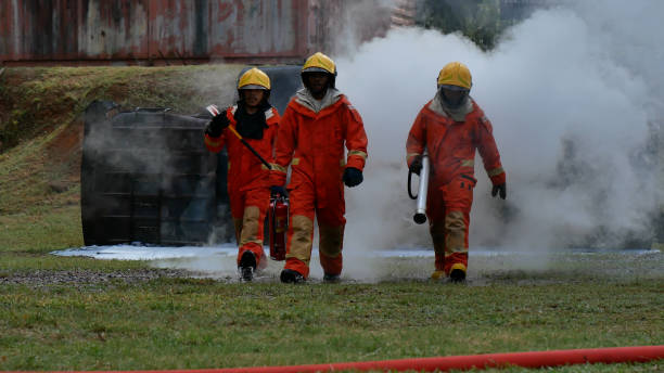 istock Firefighter fighting with flame using fire hose chemical water foam spray engine. Fireman wear hard hat, body safe suit uniform for protection. Rescue training in fire fighting extinguisher 1273900652