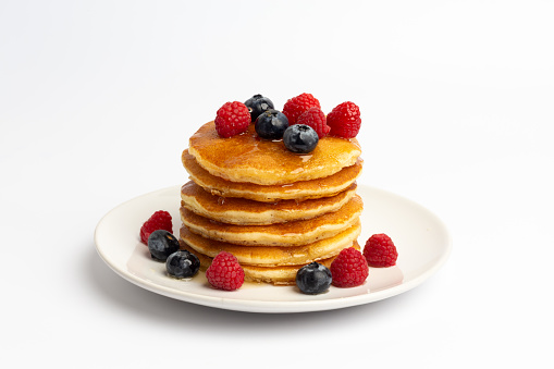 Delicious pancakes with raspberry and blueberry on White background