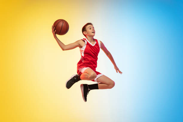 портрет молодого баскетболиста с мячом на градиентном фоне - баскетболист фотографии стоковые фото и изображения