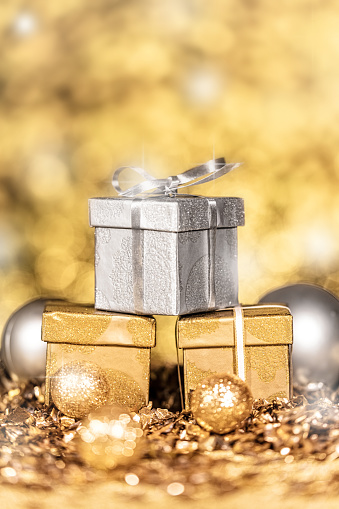 three gold and silver shiny gifts with golden sparkles