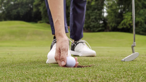 nahaufnahme von asia chinese golfer, der golfball mit der hand am loch des golfplatzes aufnimmt - golf golf course putting green hole stock-fotos und bilder