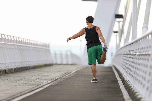 obese man stretching and warming up before running on city bridge in the morning