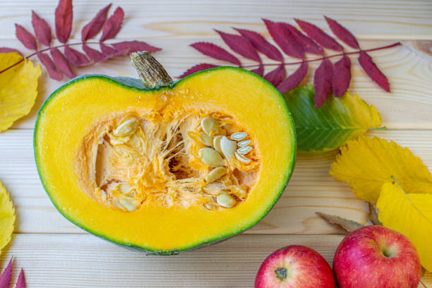 istock Cut ripe, yellow pumpkin on a wooden background with autumn leaves 1273914708