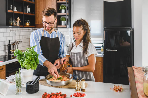 istock Young cheerful multi-ethnic couple preparing pasta together at their modern kitchen 1273915928