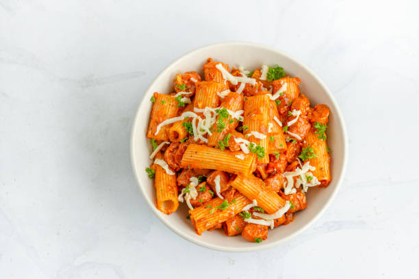 massa arrabbiata com salsicha em uma tigela no fundo branco top para baixo foto horizontal - rigatoni - fotografias e filmes do acervo