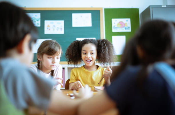 istock Group of Elementary School Pupils with pens and papers writing in classroom. Education, elementary school, learning and technology concept. 1273919136