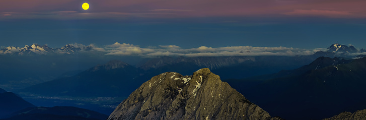 The full moon over the alpine moutains. Picture was taken on the summit Zugspitze, highest mountain in Germany.