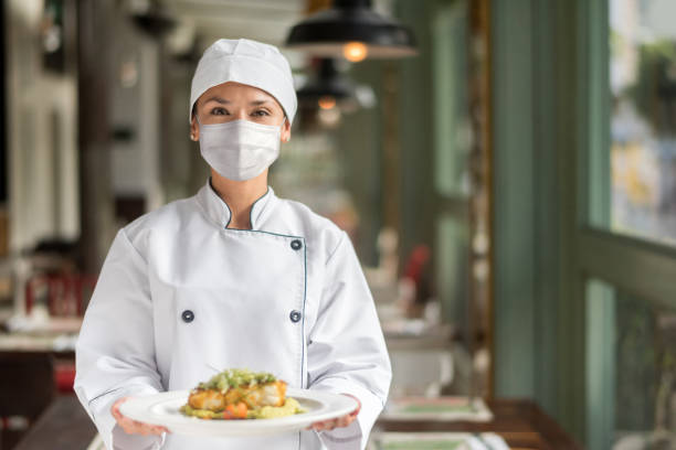 istock Chef wearing a facemask at a restaurant while presenting a plate during the pandemic 1273923095