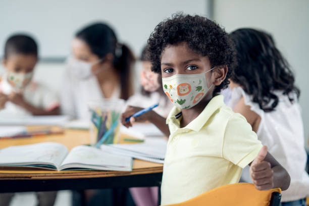 istock Happy boy at school wearing a facemask with thumbs up 1273923116