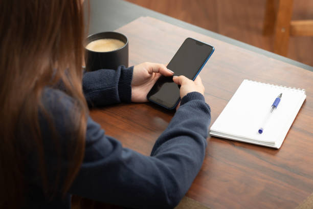 istock girl with a smartphone at a table in a cafe communicates in social networks, drinks coffee 1273923343