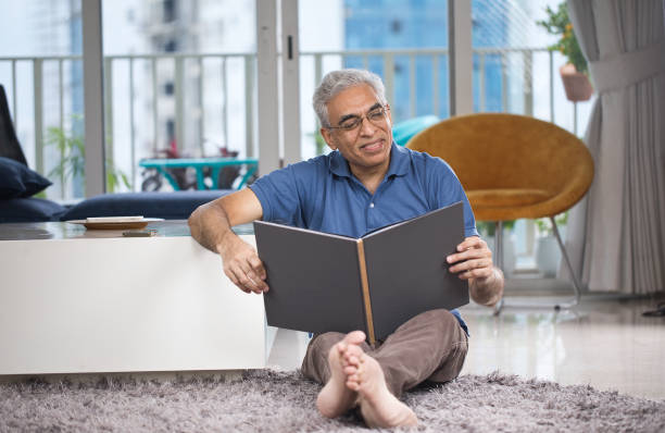 istock Senior man reading book at home 1273925022