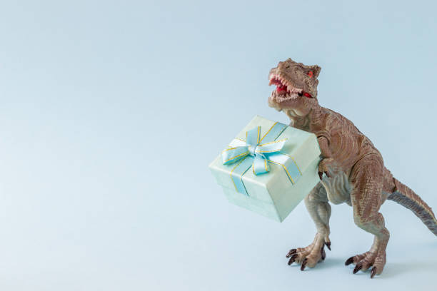 istock Dinosaur holds a gift box. Minimal concept. Idea. 1273927789
