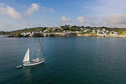 Coverack, Cornwall, UK - September 12, 2020. An aerial landscape image by drone of a luxury sailing yacht approaching the picturesque Cornish fishing village of Coverack in Cornwall, UK