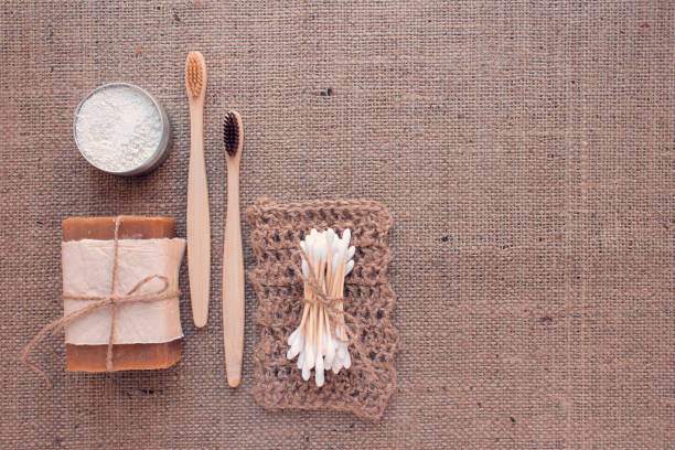 istock Set of natural bathroom tools, sustainable zero waste and lifestyle concept. Wooden toothbrushes, bamboo swabs, soap, toothpowder and handmade jute washclothes - on fabric background with copy space 1273932607