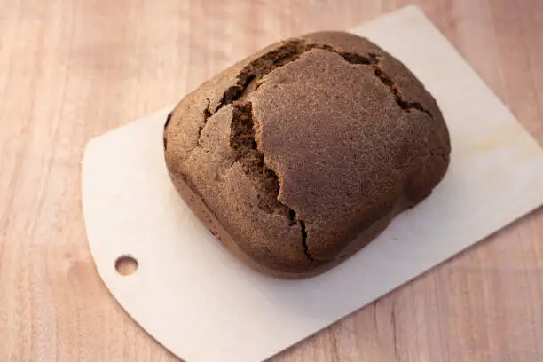 a bun of fresh black Borodino bread baked in a bread machine. Aromatic homemade cakes.