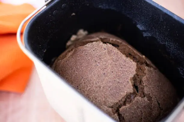 Close-up of a loaf of black Borodino bread in an electric bread maker. Aromatic homemade cakes.