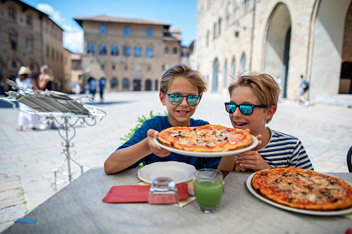 Family having lunch in beautiful Italian town of Volterra. 
Little boys are eating delicious italian pizza.
D850