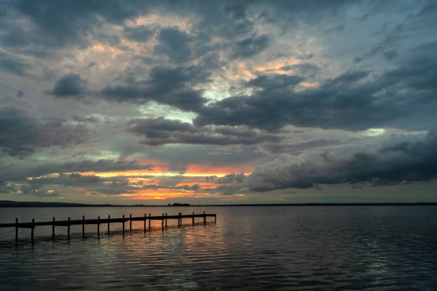 istock Silhouette of jetty backlit on lake at dusk 1273939619