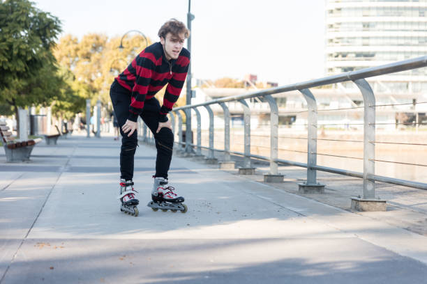 A young male roller skater is catching his breath at a waterfront park