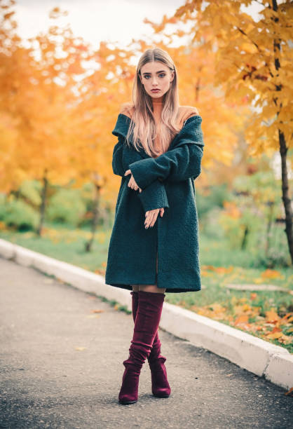 schöne junge frau mit lockeren haaren in einem gestrickten herbstpullover und mantel im park vor dem hintergrund von gelbem laub. - 18 23 monate stock-fotos und bilder