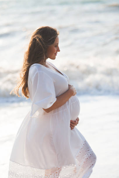 istock Pregnant woman at beach 1273940934