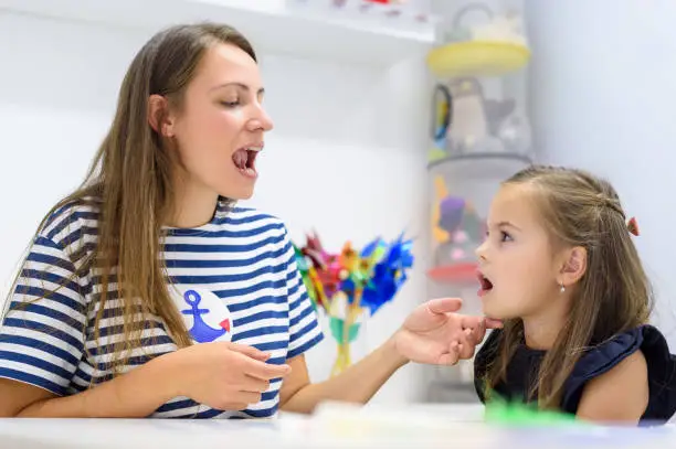 Children speech therapy concept. Preschooler practicing correct pronunciation with a female speech therapist.