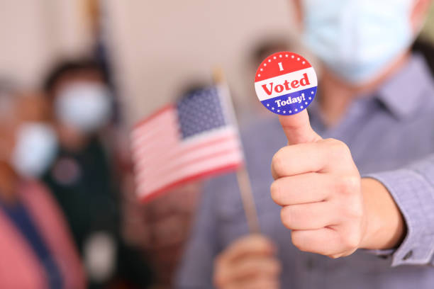 Man votes in USA election wearing mask and I Voted sticker.