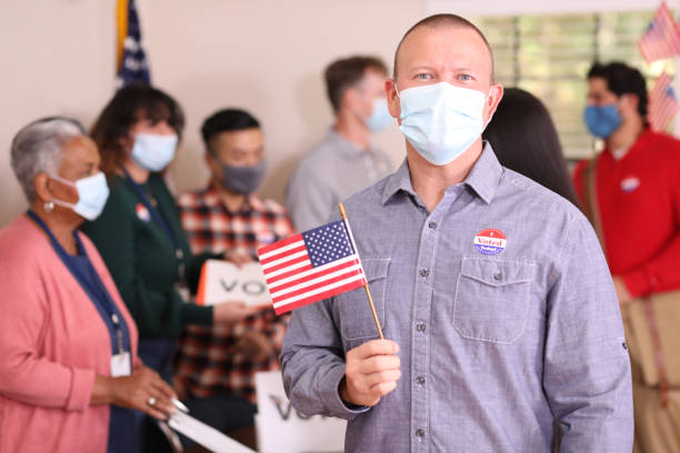 istock Man votes in USA election wearing mask. 1273942275
