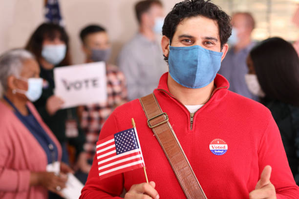 istock Latin descent man votes in USA election wearing mask. 1273942415