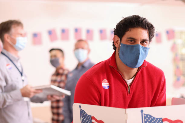 istock Latin descent man votes in USA election wearing mask. 1273942962