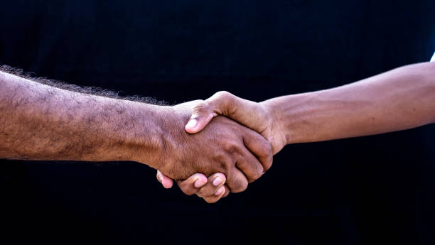 istock people concepts. Two men shaking hands isolated on black backgrounds 1273943963