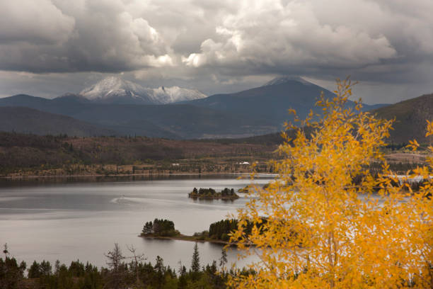 Snow dusted Mount Guyot Lake Dillion reservoir fall yellow aspen Colorado autumn Rocky Mountains Rising over 13,000 feet, storm clouds roll by a snow dusted Mount Guyot and Bald Mountain which rise behind the Lake Dillon Reservoir with fall colors in Summit County, Colorado. frisco colorado stock pictures, royalty-free photos & images