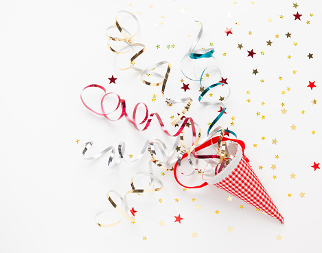 Festive composition with colorful confetti, Christmas ornaments and streamers on white. Celebration concept ideas for Christmas, New Year. Flat lay, copy space.
