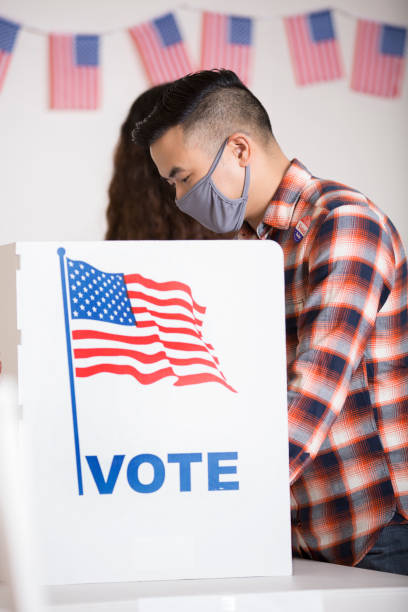 istock Vote Polling Place.  Everybody wears a protective face mask. 1273975455