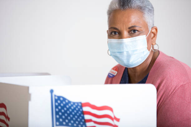 istock Vote Polling Place.  Everybody wears a protective face mask. 1273975494