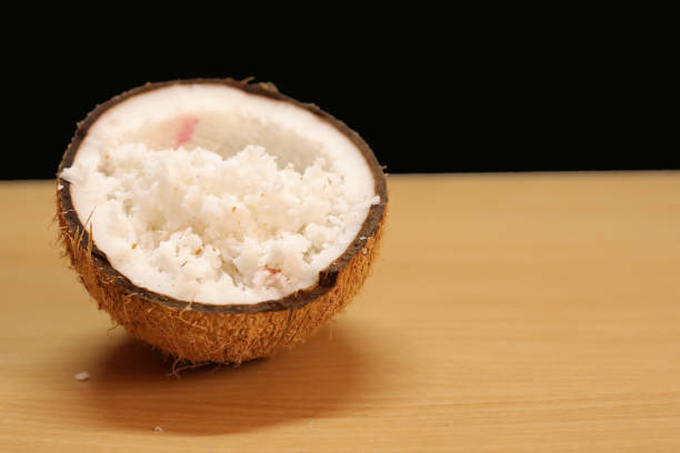 istock Coconuts with coconut flakes are isolated on a wooden table on a black backgrounds 1273976239