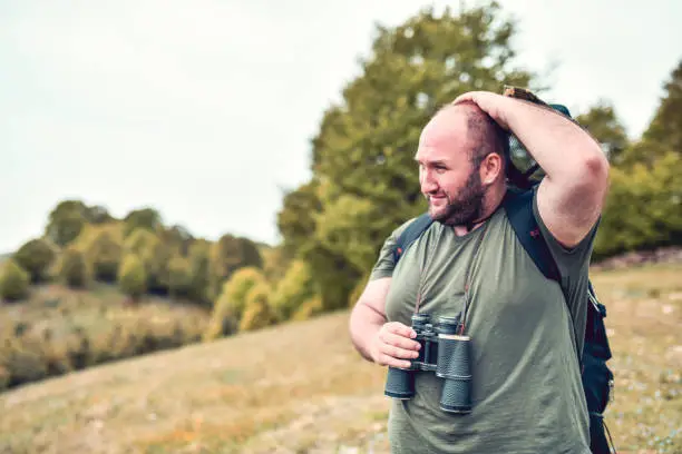 Photo of Worried Bald Hiker Struggling To Find His Way In Forest With Binoculars