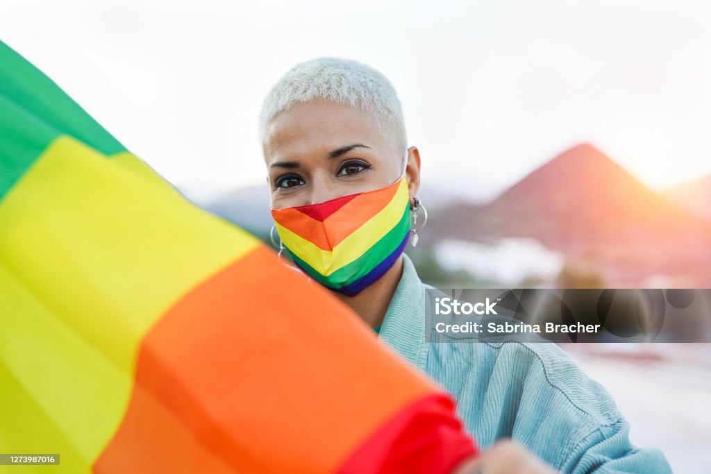 Beautiful latin lesbian woman with LGBT pride rainbow flag outdoor LGBTQIA Rights Stock Photo