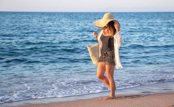istock Beautiful boho model in a hat with a wicker bag on the beach 1273995895