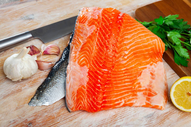 istock Salmon fillet on cutting board with lemon and parsley 1274016110