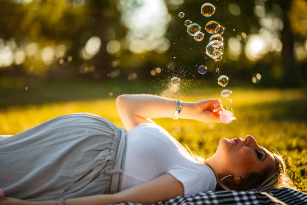 istock Pregnant woman blowing bubbles in park 1274052148