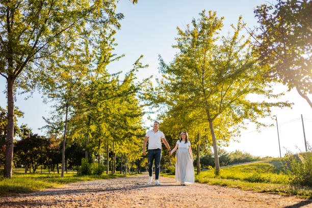 pregnant couple walking in park - couple human pregnancy sunset walking imagens e fotografias de stock