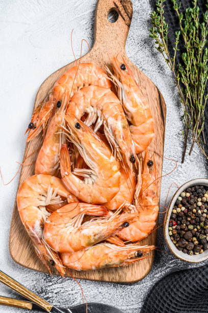 istock Cooked fresh giant prawns on a wooden chopping Board. White background. Top view 1274116838