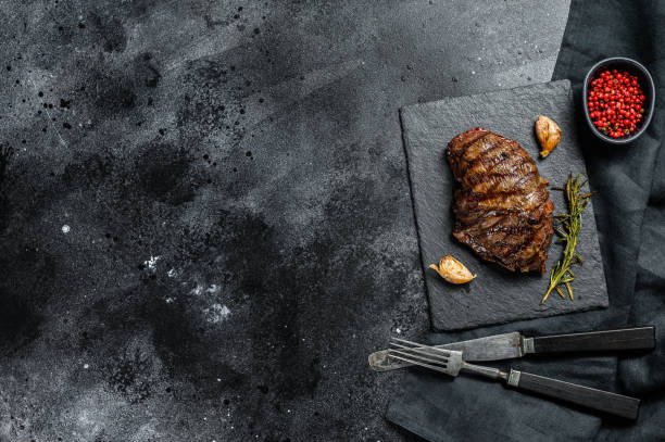 istock Grilled Top Blade steak on a stone Board, marbled beef. Black background. Top view. Copy space 1274117177