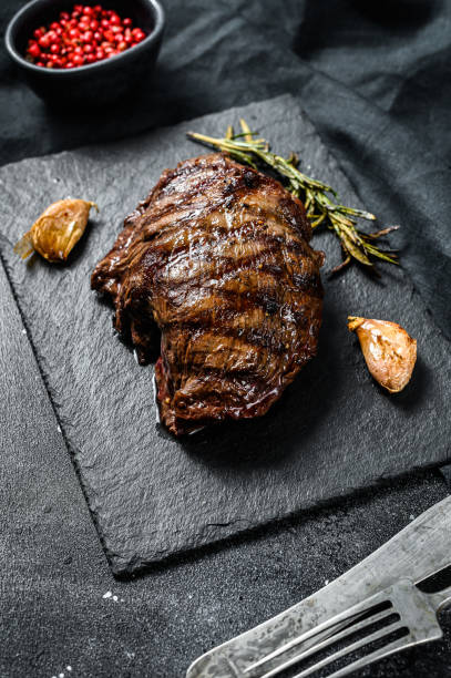istock Grilled Top Blade steak on a stone Board, marbled beef. Black background. Top view 1274126721