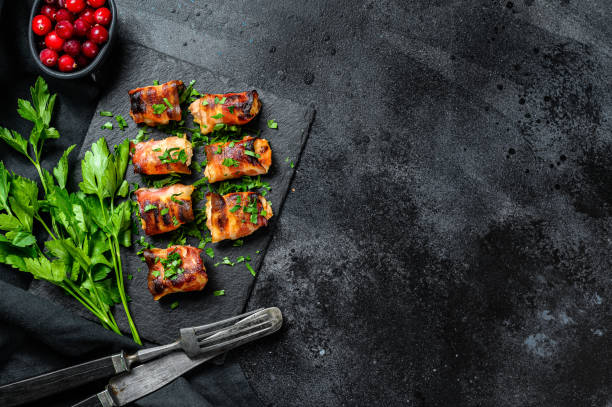 istock stuffed chicken breasts, fillets rolled in bacon. Black background. Top view. Copy space 1274128821