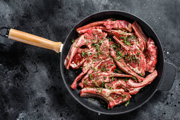 chuletas de costilla de cordero fresco crudo marinadas con tomillo y menta en una sartén. fondo negro. vista superior. copiar espacio - veal rack fotografías e imágenes de stock