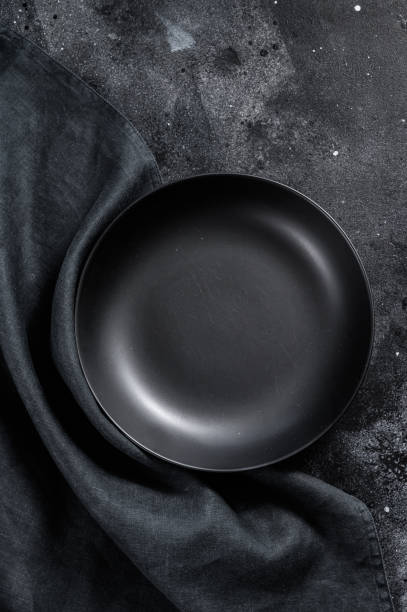 istock Black plate and a towel on textured black background.  Top view. Copy space 1274143819